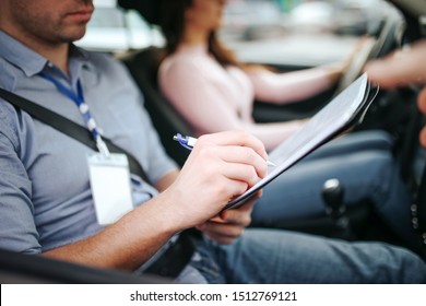 Male Auto Instructor Takes Exam In Young Woman. Close Up Of Man Writing On Paper. Passing Practical Test. Young Woman Driving With Confidence.