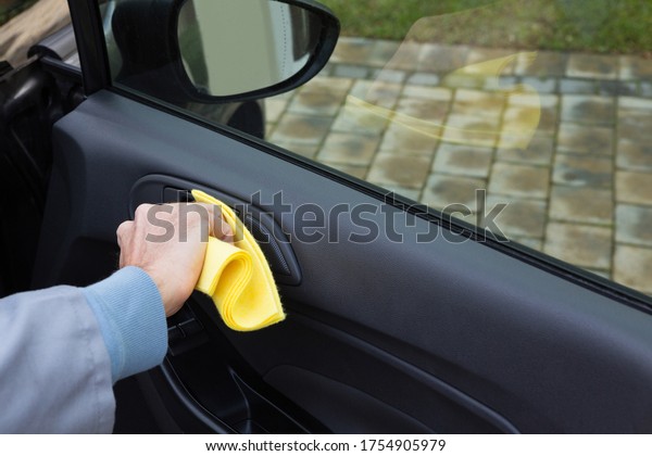 Male auto service\
staff cleaning car door