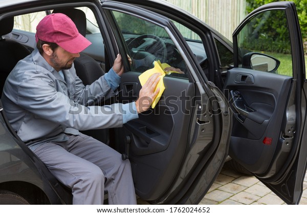 Male auto service\
staff cleaning car door