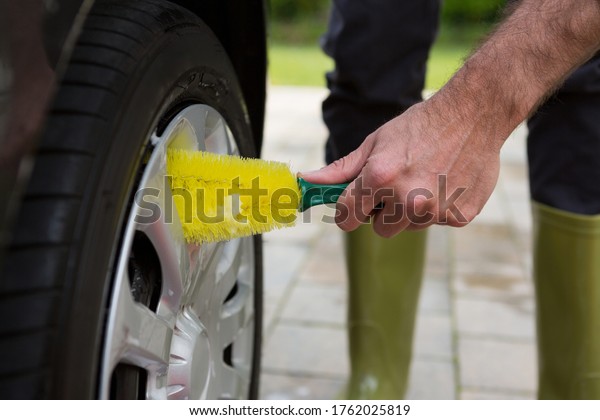 Male auto\
service staff washing a tyre with\
brush