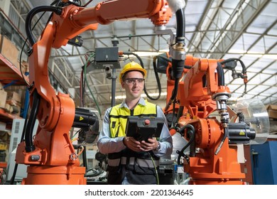 Male automation engineer testing robot arm welding machine by using remote control board for operating at industrial factory