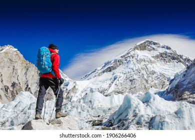 Male backpacker enjoying the view on mountain walk in Himalayas. Face to face with mount Everest, Earth's highest mountain. Travel, adventure, sport concept