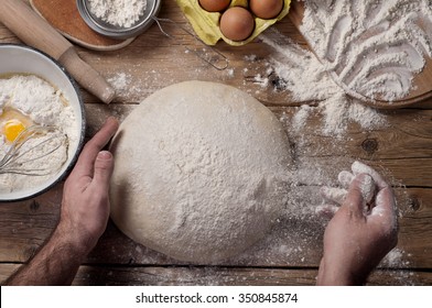 Male baker prepares bread. Male baker sprinkle the dough with flour. Making bread. Top view. Rustic style - Powered by Shutterstock