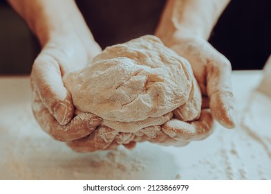 male baker's hands holding kneaded dough sprinkled with flour close-up. hands dough craft bakery