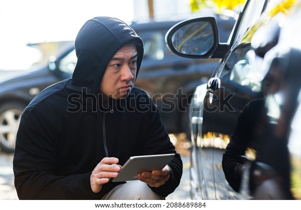 male bandit thief car thief asian uses a tablet to
turn off the car alarm