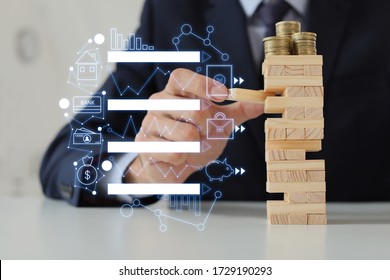 Male bank manager with tower made of blocks and coins at table in office. Concept of planning, risk and strategy in business