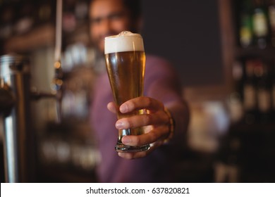 Male Bar Tender Giving Glass Of Beer At Bar Counter