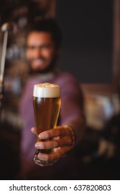 Male Bar Tender Holding Glass Of Beer At Bar Counter