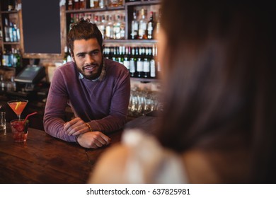 Male Bar Tender Interacting With Customer At Pub