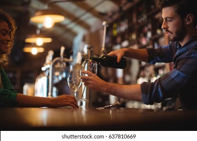 Male Bar Tender Pouring Wine In Glasses At Bar Counter