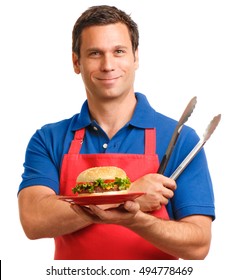 Male barbecue Chef man with utensils wearing a red apron blue polo shirt and holding a cheeseburger isolated on white background