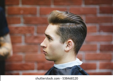 Male barber makes hair styling using a dryer of a young man. - Powered by Shutterstock