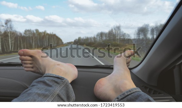 male bare feet on the dashboard of a moving\
car. traffic on the\
motorway.