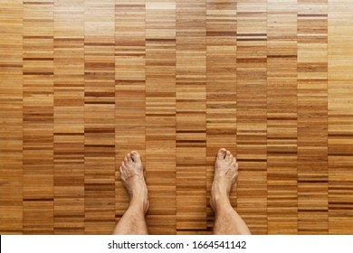 Male Bare Feet Stand On A Wooden Floor, Top View