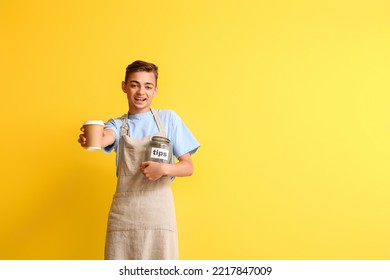 Male Barista With Cup Of Coffee And Tip Jar On Yellow Background