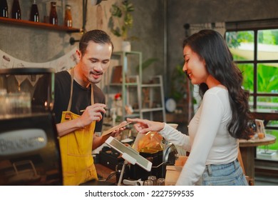 Male barista is explaining the menu in digital tablet to customer. Female customer is ordering by a touch screen menu. Technology service. Concept of cyberspace, cafe or bakery counter bar. - Powered by Shutterstock