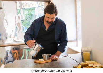 Male Barista Preparing Fresh Espresso In Coffee Maker For Customer In A Fancy Coffee Shop. Cafe Owner Serving A Client At The Coffee Shop.