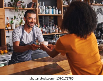 Male barista serves coffee cup to female customer in cafe - Powered by Shutterstock