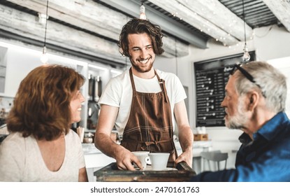 Male barista working in coffee shop, serving customers, elderly couple. University student working part-time in cafe. - Powered by Shutterstock