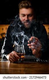 Male Bartender Holding In His Hands A Glass Of Strong Alcoholic Drink And Smoking Cuban Cigar