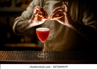 Male Bartender Holds Lemon Peel In His Hands And Sprinkles On Glass With Bright Cocktail.