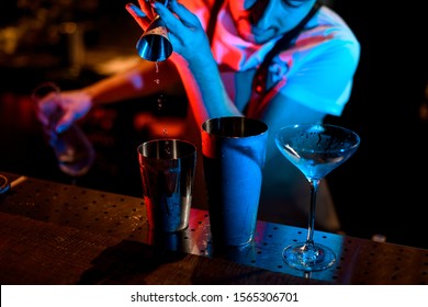 Male Bartender Pouring Alcohol Cocktail With Jigger In Neon Lights