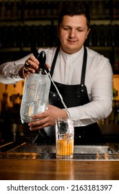 Male Bartender Skilfully Adds Carbonated Liquid From Siphon To Transparent Glass With Cold Alcoholic Cocktail On Bar Counter