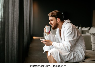 Male in bathrobe relaxing while drinking tea