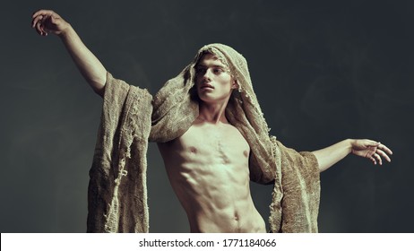 Male beauty concept. Art portrait of of a courageous muscular man with burlap on his face and body. Studio shot on a black background.