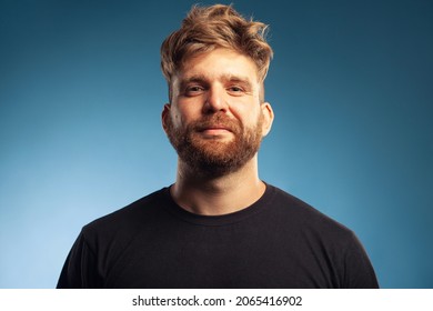 Male beauty concept. Emotive portrait of proud charismatic active 30-year-old man posing over blue background. Perfect haircut. Hipster style. Close up. Studio shot