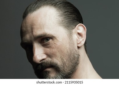 Male Beauty Concept. Fabulous At Any Age. Portrait Of 45-year-old Man Standing Over Dark Gray Background. Hair Brushed Back. Rocker, Biker Style. Scar On Forehead. Close Up. Studio Headshot