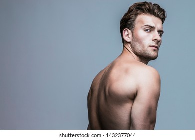 Male beauty concept. Portrait of handsome young man with stylish haircut posing over gray background. Perfect hair & skin. Tough guy. Vogue style. Close up. Studio shot