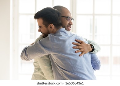 Male best friends greeting standing indoors, diverse young guys meet hugging feels happy not see each other for long time, multiracial friendship, good friendly relations, support and reunion concept - Shutterstock ID 1653684361