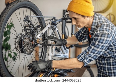 A male bicycle mechanic in the workshop disassembles a mountain bike and repairs it. Maintenance concept, preparation for the new season. - Powered by Shutterstock