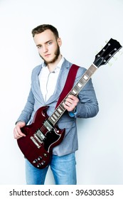 Male blue-eyed handsome musician holding red electric guitar