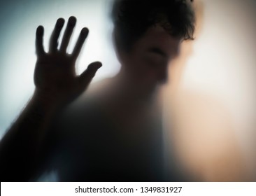 Male Blurred Silhouette Through Frosted Glass. Dramatic Film Grain