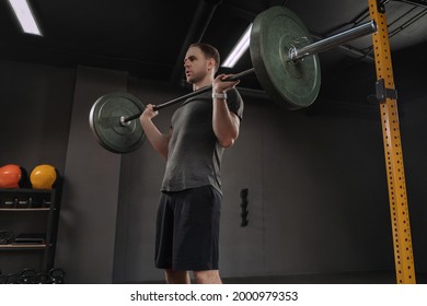 Male bodybuilder doing military press at dark gym. Weightlifter holding barbell on chest, preparing to lift it overhead or do front squat.Muscular fitness man lifting weight, having crossfit training - Powered by Shutterstock