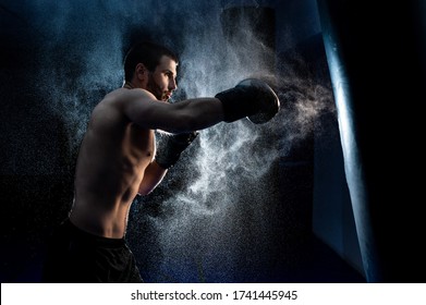 Male boxer boxing in punching bag. shot in smoke. Black background - Powered by Shutterstock