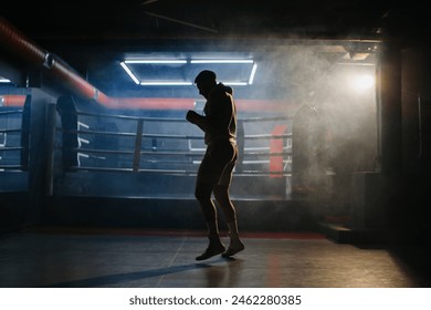 A male boxer is boxing with a shadow on the background of a boxing ring. A boxer practices his punches in a boxing studio. - Powered by Shutterstock