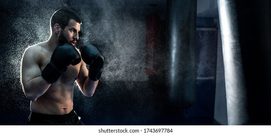 Male boxer hitting a huge punching bag at a boxing studio. man boxer training hard