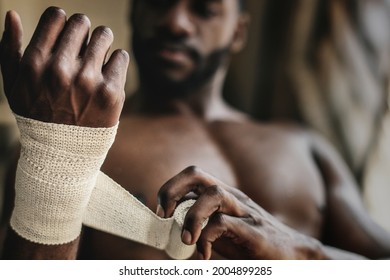 Male boxer putting a strap on his hand - Powered by Shutterstock