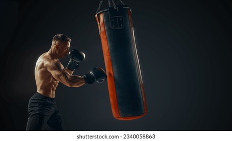 Male boxer training with punching bag isolated. Young attractive boxer training on punching bag. Male boxer exercise before fight. Boxer hits punching bag Defence.