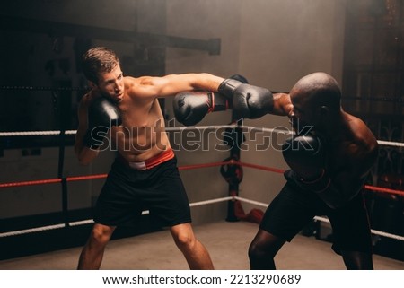 Male boxers throwing punches at each other during a fight in a boxing ring. Two athletic young men having a boxing match in a fitness gym.