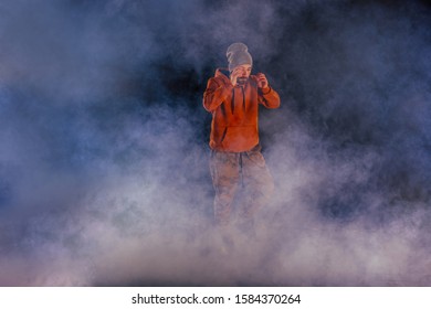 Male breakdancer prepares to dance on the stage wearing a hat and casual clothes with a lot of smoke in the background. - Powered by Shutterstock