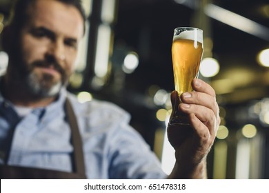 Male brewery worker examining small glass of beer - Powered by Shutterstock