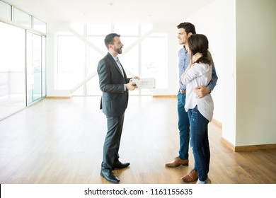 Male broker discussing with couple while standing in new house