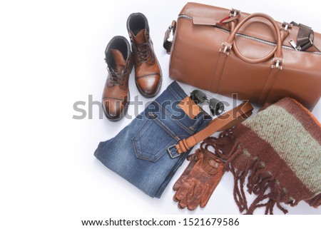 Male brown boots shoe with large leather handbag ,blue jeans ,scarf, gloves, belt, sunglasses on white background 


