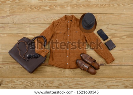 Male brown shoes with large leather handbag ,hat,phone, purse on wooden background 


