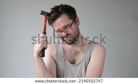 Male builder in big glasses scratches his head with a hammer. I do not know how to repair it.