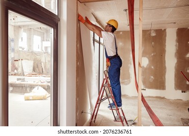 Male Builder Hanging Wallpaper On The Wall